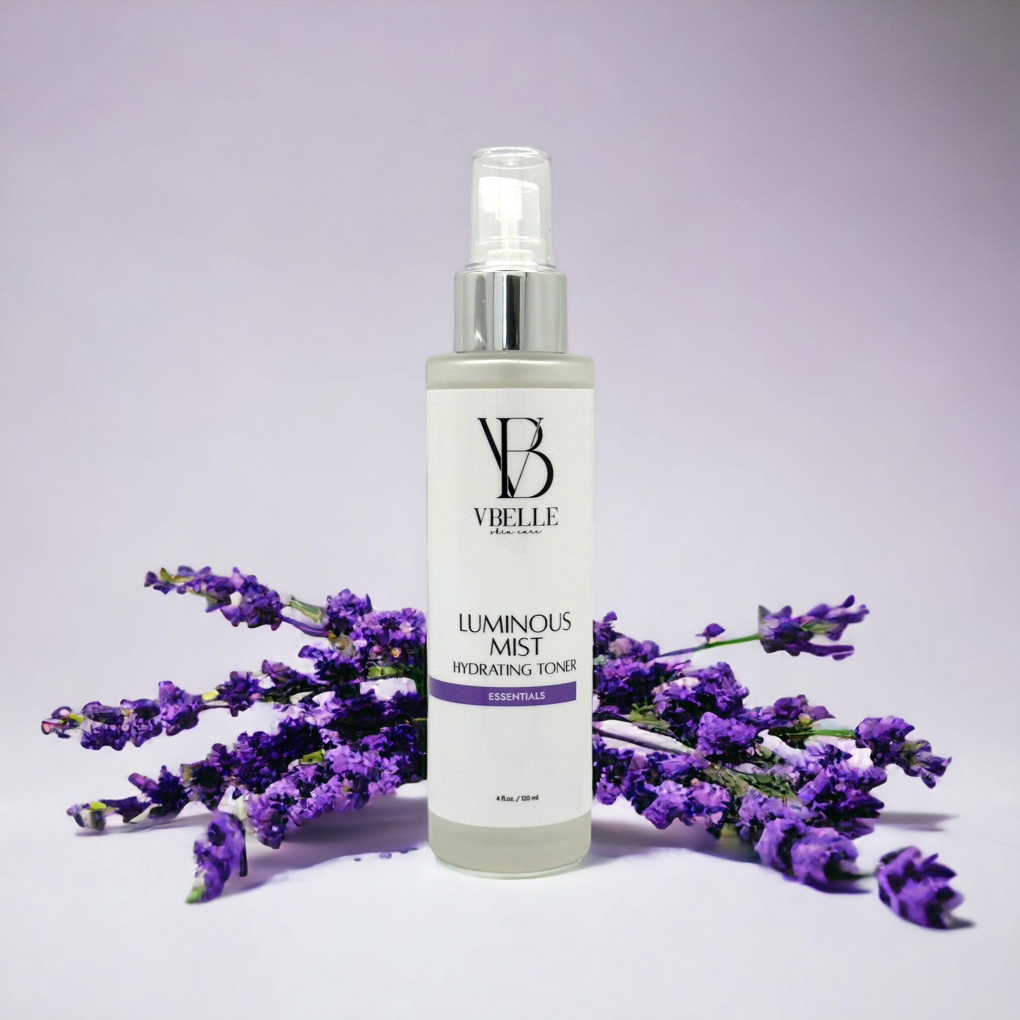 Organic Luminous Mist Hydrating Toner 4 fl oz glass bottle with Lavender flowers in the background and a light violet backdrop