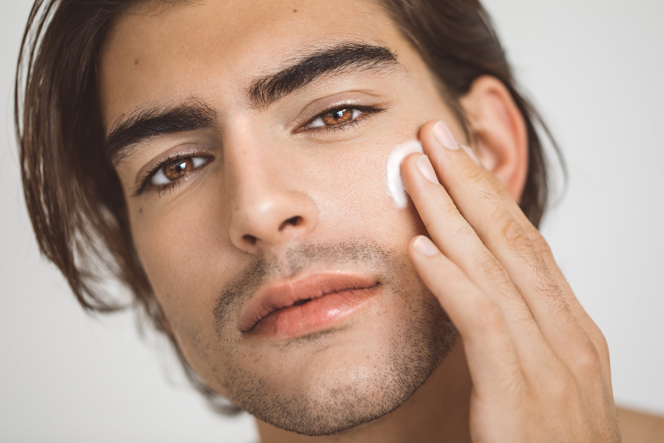young male applying face moisturizer